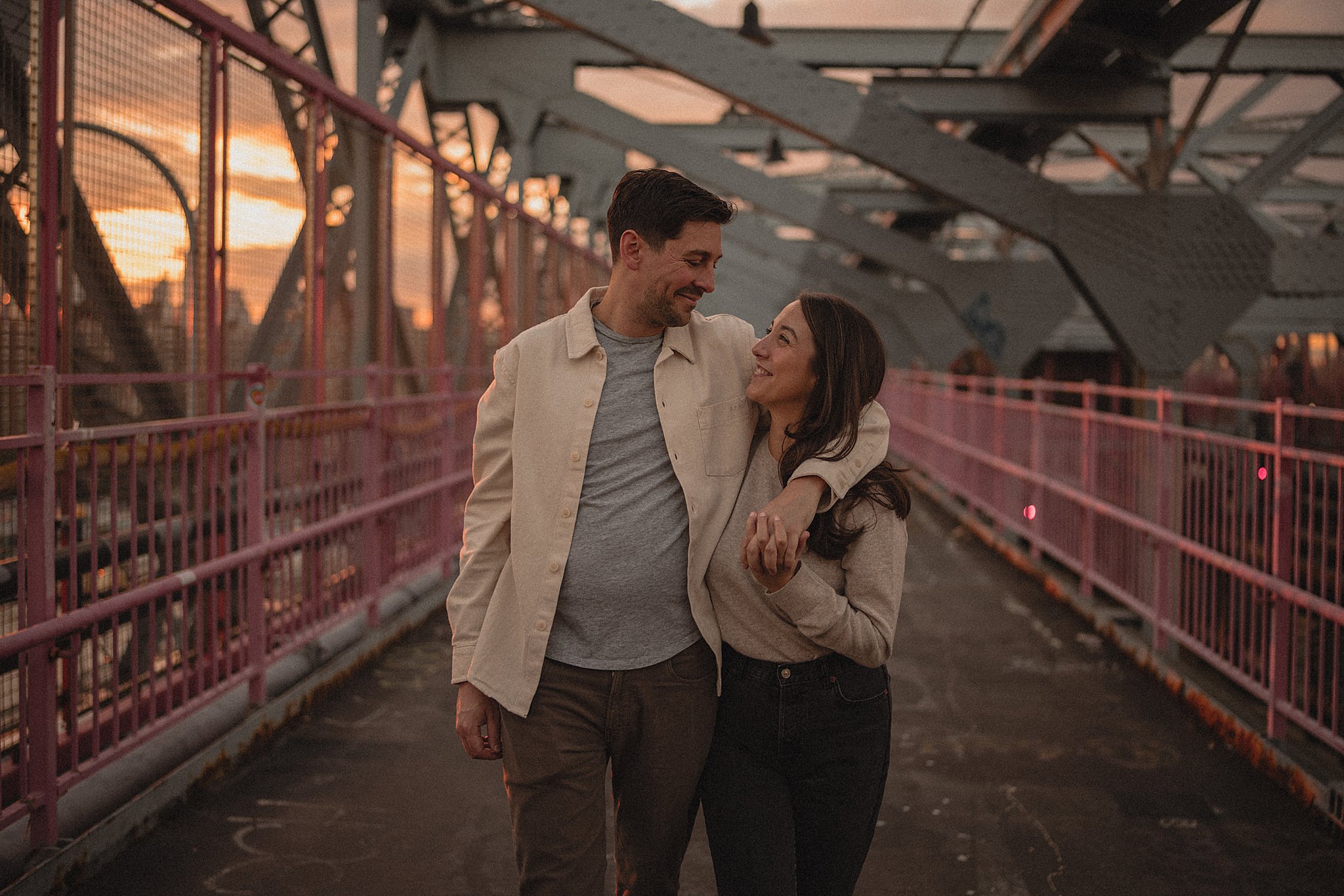 engaged couple walks the williamsburg bridge during their engagement session in brooklyn